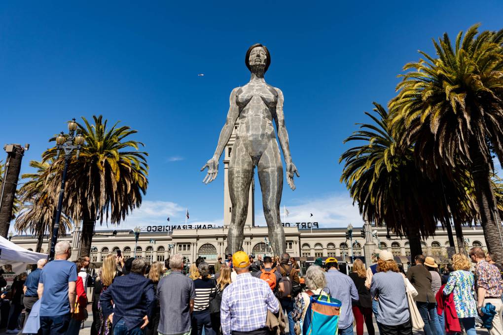giant metal mesh sculpture of nude woman in front of SF Ferry Building, crowd below